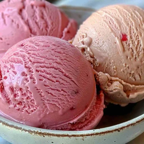 Best Ninja Creami Ice Cream Recipes (Healthy & Easy at Home) 4 Creamy strawberry Ninja Creami ice cream scoops in a ceramic bowl, showing a smooth, rich texture and vibrant pink color — Ninja Creami ice cream recipes.
