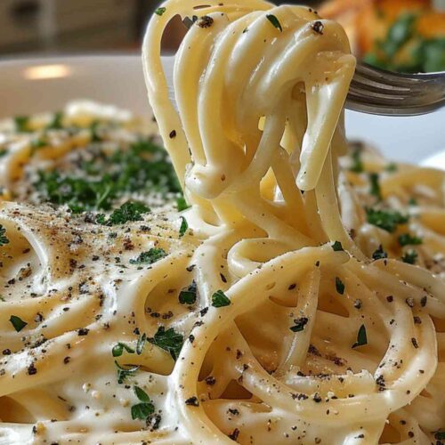 Alfredo Sauce with Cream Cheese 5 Fettuccine coated in Alfredo sauce with cream cheese, lifted by a fork to show the creamy texture and topped with parsley and black pepper.