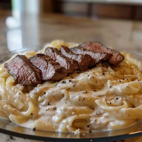 Steak Alfredo Recipe – Creamy Comfort, Foolproof and Easy 5 Plate of creamy Alfredo pasta topped with sliced steak, served in a home kitchen setting for a classic steak Alfredo recipe.